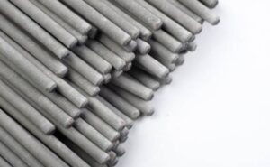 Pile of gray metal dowel rods arranged diagonally on a white surface, viewed close-up.